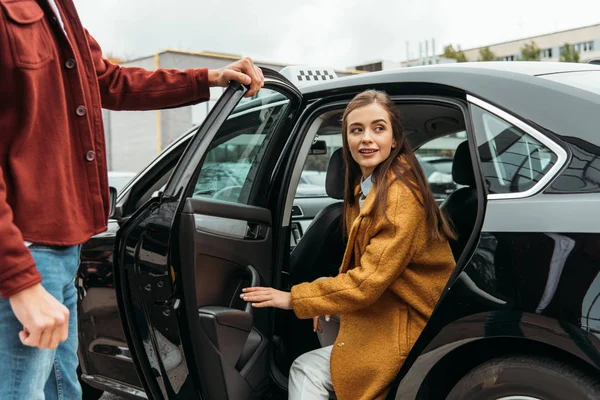 Водій таксі відкриває двері автомобіля для усміхненої жінки — стокове фото