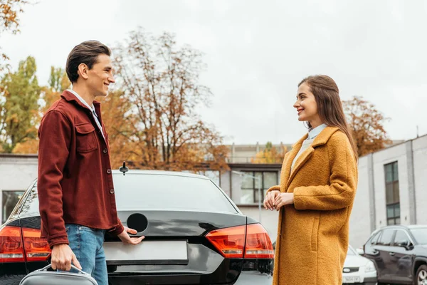 Taxi driver helping woman with baggage beside car trunk — Stock Photo