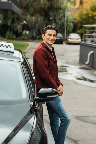 Motorista de táxi sorrindo olhando para a câmera ao lado do carro — Fotografia de Stock