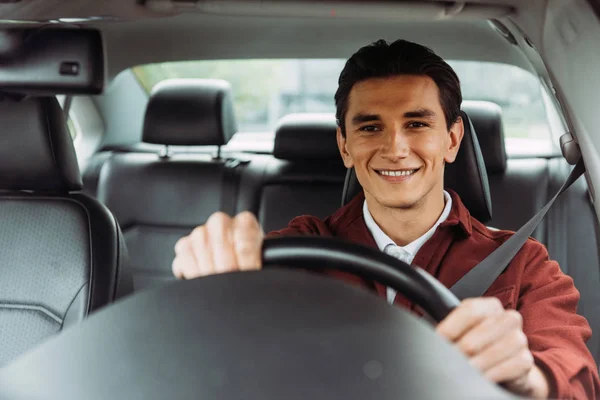 Smiling handsome man holding steering wheel of car — Stock Photo