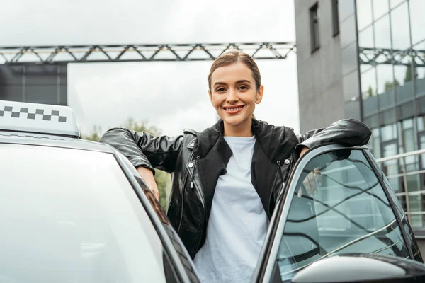 Жінка таксист посміхається на камеру біля машини — стокове фото