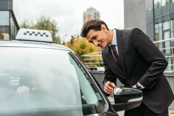 Handsome businessman pointing on something to taxi driver on street — Stock Photo