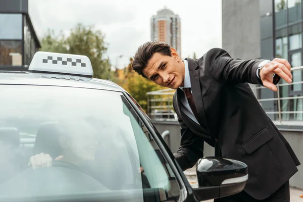 Businessman pointing on something to taxi driver on street — Stock Photo