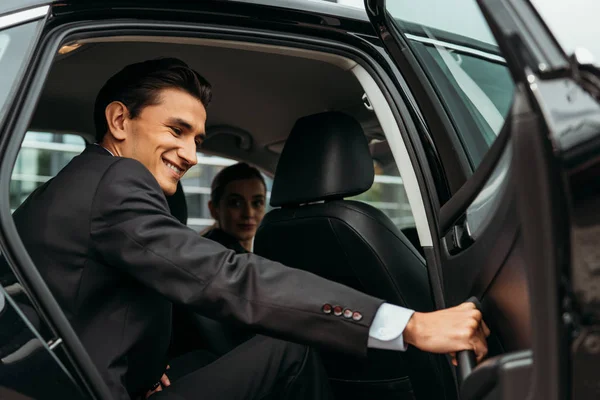 Hombre de negocios sonriente cerrando la puerta de pasajero de taxi - foto de stock