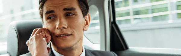 Panoramic shot of businessman talking on smartphone in taxi — Stock Photo