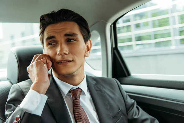 Hombre de negocios guapo hablando en el teléfono inteligente en taxi - foto de stock