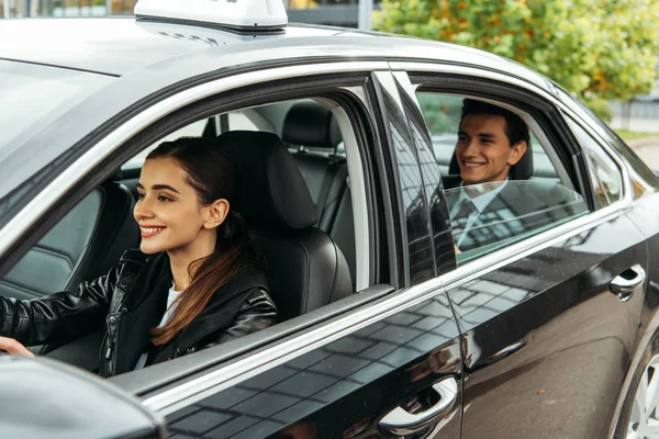 Sorridente tassista femminile e uomo d'affari in auto — Foto stock