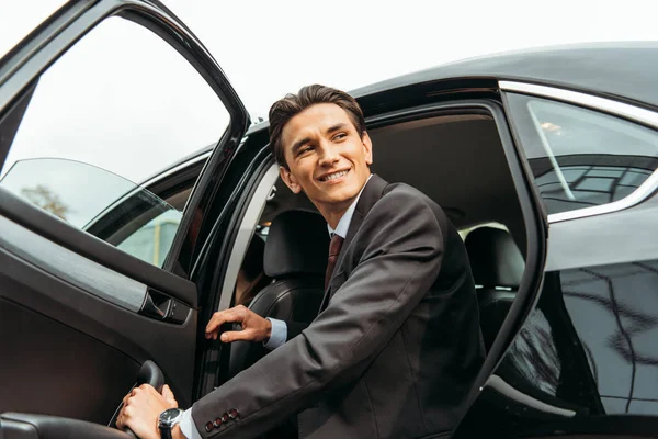 Tiefansicht eines lächelnden Geschäftsmannes, der aus dem Taxi steigt — Stockfoto