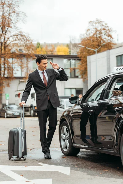 Geschäftsmann mit Koffer lächelt Taxifahrer an — Stockfoto