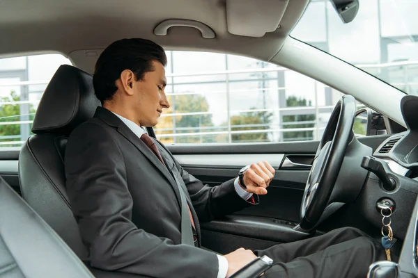 Schöner Geschäftsmann schaut auf Armbanduhr im Drohnenauto — Stockfoto