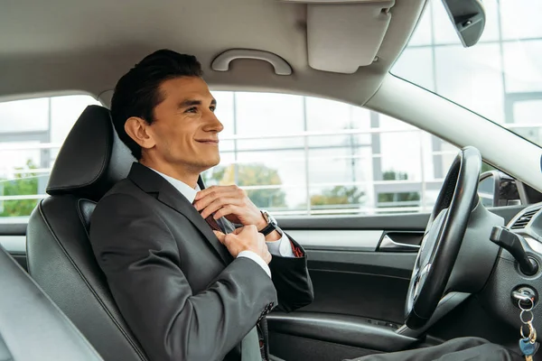 Lächelnder Geschäftsmann justiert Krawatte und blickt in Spiegel von Drohnenauto — Stockfoto