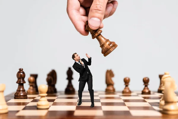 Cropped view of man playing chess and frightened marionette looking at figure isolated on grey — Stock Photo