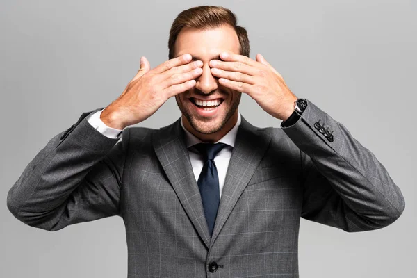 Smiling businessman in suit obscuring face isolated on grey — Stock Photo