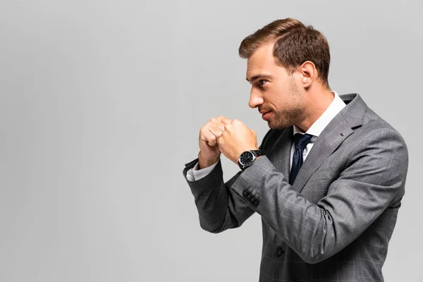 Side view of handsome businessman in suit punching isolated on grey — Stock Photo