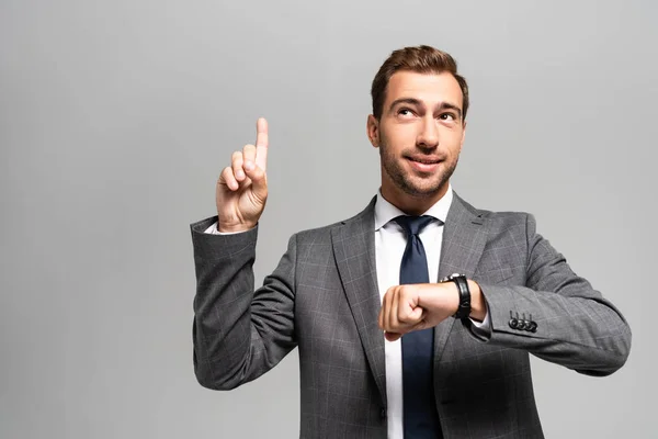 Gutaussehender und lächelnder Geschäftsmann im Anzug zeigt Ideenschild isoliert auf grau — Stockfoto