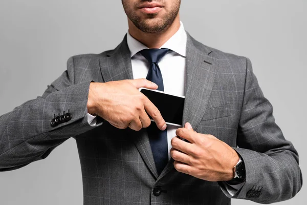 Cropped view of businessman in suit hiding smartphone isolated on grey — Stock Photo