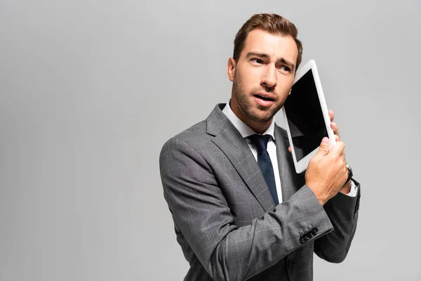 Guapo hombre de negocios en traje usando tableta digital aislado en gris - foto de stock