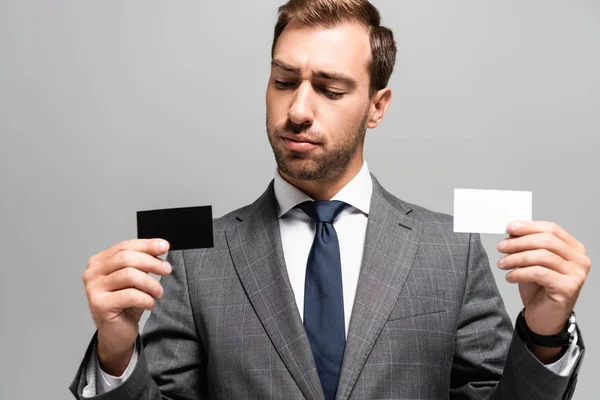 Schöner Geschäftsmann im Anzug mit Visitenkarten isoliert auf grau — Stockfoto