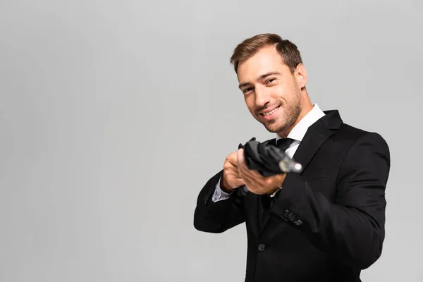 Foyer sélectif de beau et souriant homme d'affaires en costume tenant parapluie isolé sur gris — Photo de stock