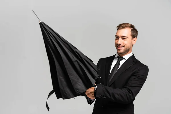 Homme d'affaires beau et souriant en costume ouverture parapluie isolé sur gris — Photo de stock