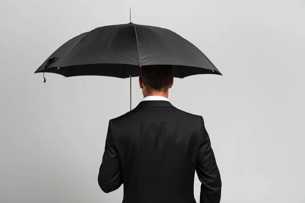 Vista trasera del hombre de negocios en traje con paraguas aislado en gris - foto de stock