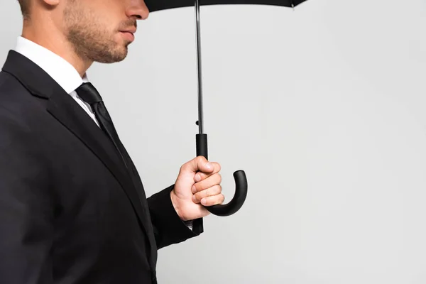 Vista recortada de hombre de negocios en traje con paraguas aislado en gris - foto de stock