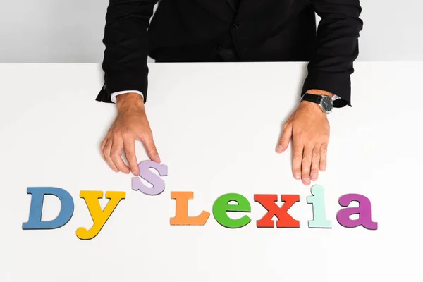 Cropped view of businessman in suit sitting near dyslexia lettering — Stock Photo