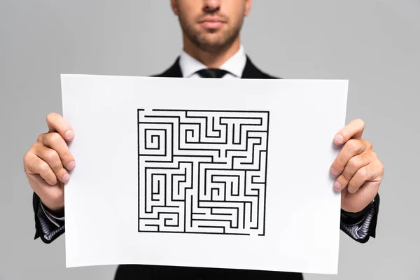 Cropped view of businessman holding paper with labyrinth isolated on grey — Stock Photo