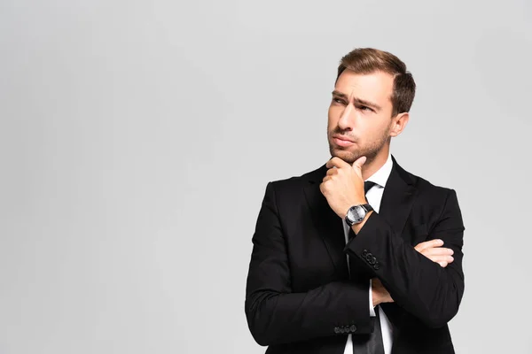 Hombre de negocios guapo y pensativo en traje mirando hacia arriba aislado en gris - foto de stock