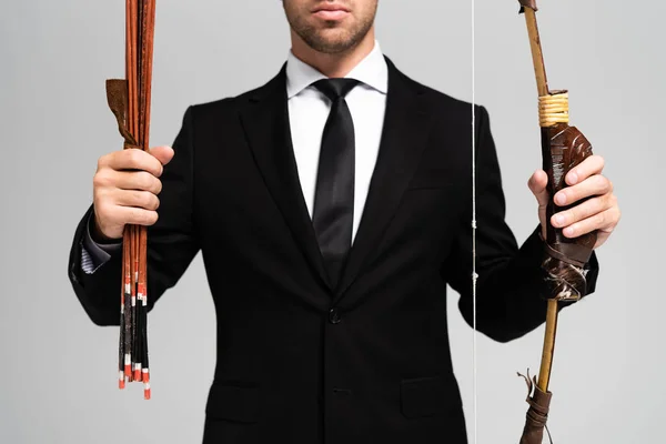 Vista recortada de hombre de negocios en traje con arco y flechas aisladas en gris — Stock Photo