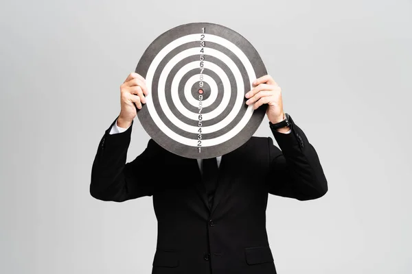 Businessman in suit obscuring face with darts board isolated on grey — Stock Photo