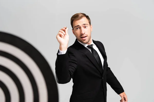 Selective focus of businessman in suit playing darts isolated on grey — Stock Photo