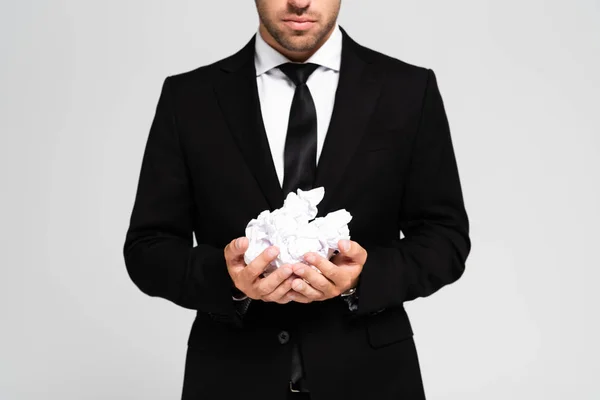 Vista recortada del hombre de negocios en traje sosteniendo papeles arrugados aislados en gris - foto de stock