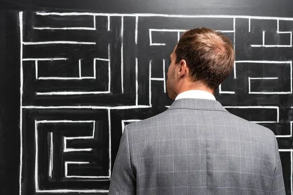 Back view of businessman in suit looking at labyrinth — Stock Photo