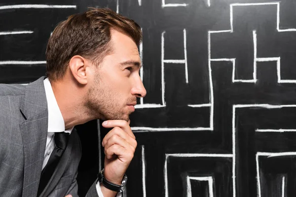 Side view of pensive businessman in suit looking at labyrinth — Stock Photo