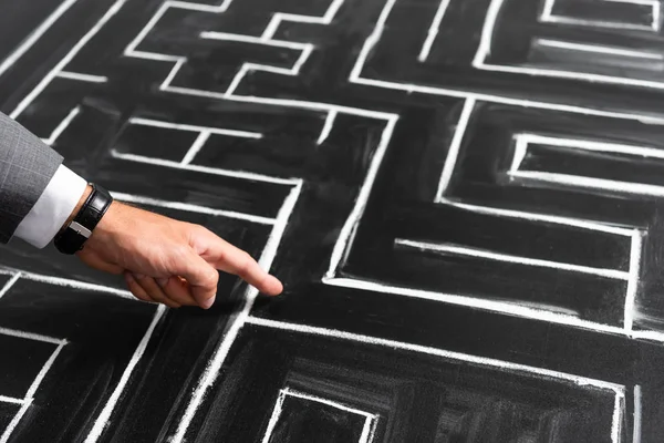 Cropped view of businessman pointing with finger at labyrinth — Stock Photo