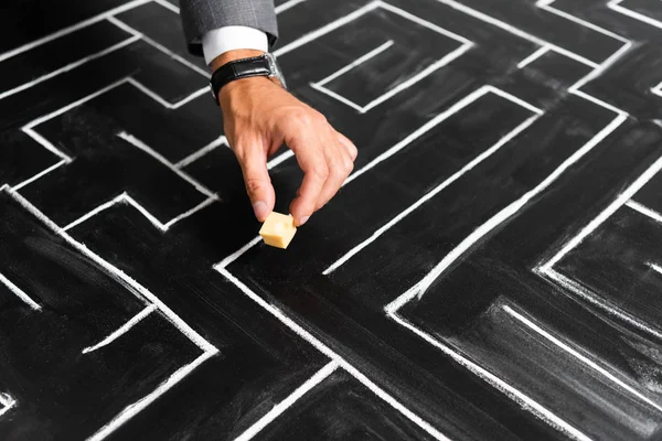 Cropped view of businessman putting cut cheese on labyrinth — Stock Photo