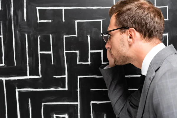 Back view of handsome businessman in suit looking at labyrinth — Stock Photo