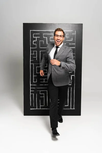 Handsome and smiling businessman in suit running near labyrinth — Stock Photo