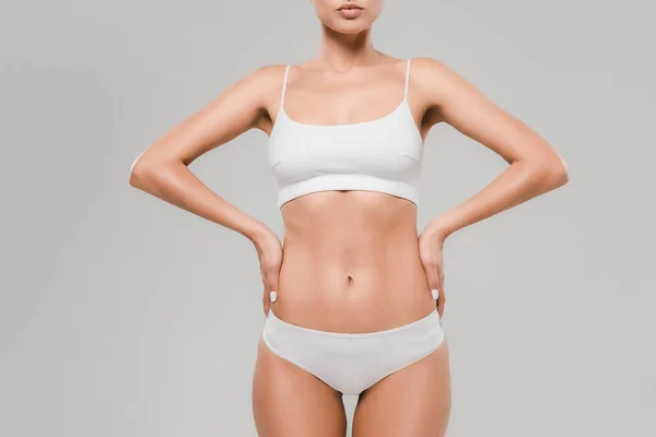 Vue recadrée de belle femme mince en sous-vêtements posant avec les mains sur les hanches isolées sur gris — Photo de stock