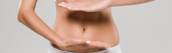 Vue partielle de belle femme mince en sous-vêtements posant avec les mains près du ventre isolé sur gris, prise de vue panoramique — Photo de stock