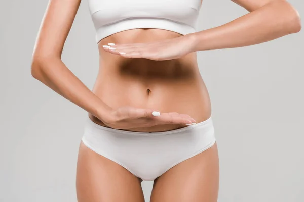 Vue partielle de belle femme mince en sous-vêtements posant avec les mains près du ventre isolé sur gris — Photo de stock