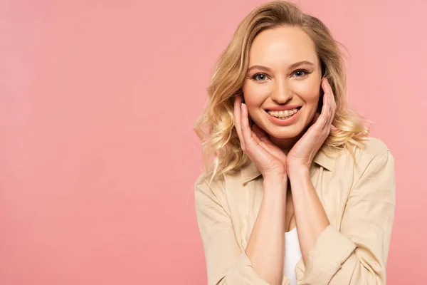 Lächelnde Frau mit Zahnspange und Händen in Gesichtsnähe isoliert auf rosa Hintergrund — Stockfoto