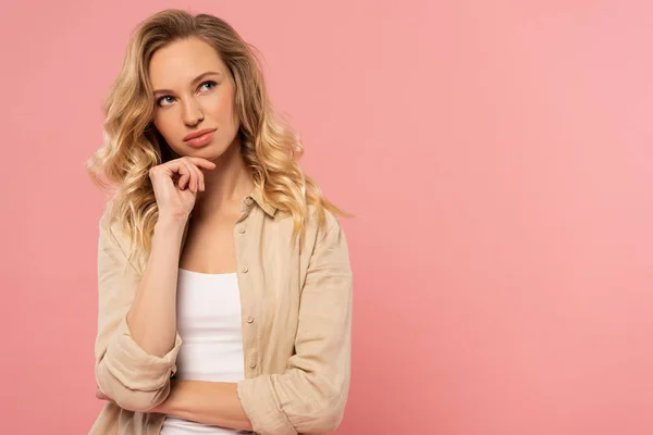 Donna bionda pensierosa con mano sul mento isolata sul rosa — Foto stock