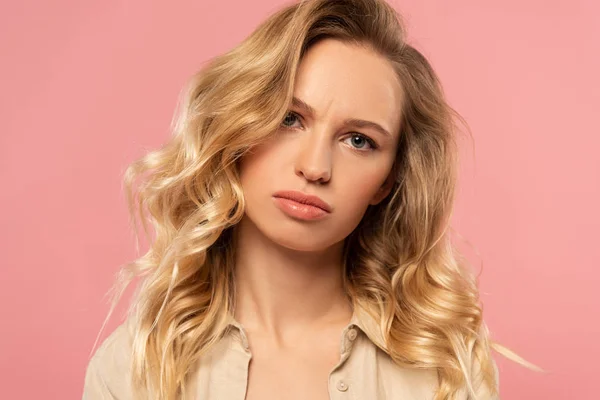 Unzufriedene blonde Frau blickt isoliert auf rosa Kamera — Stockfoto