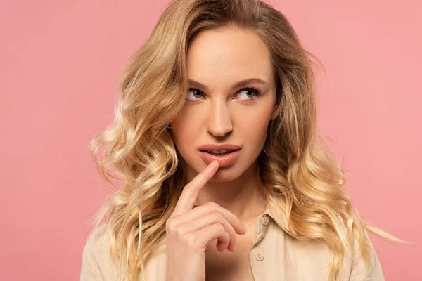 Pensive woman with finger beside mouth isolated on pink — Stock Photo