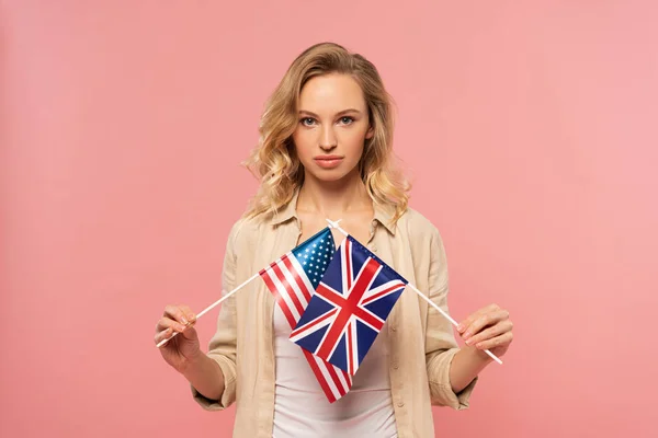 Attractive blond woman holding american and Britain flags isolated on pink — Stock Photo