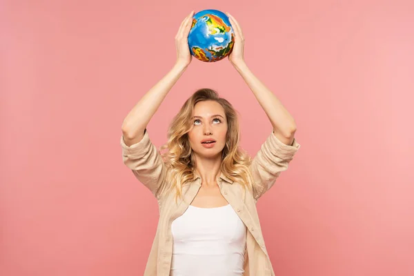 Mujer rubia sosteniendo globo por encima de la cabeza aislado en rosa - foto de stock