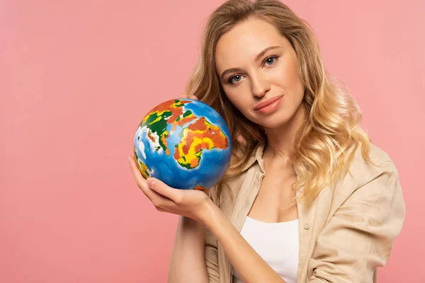 Sourire femme blonde tenant globe isolé sur rose — Photo de stock