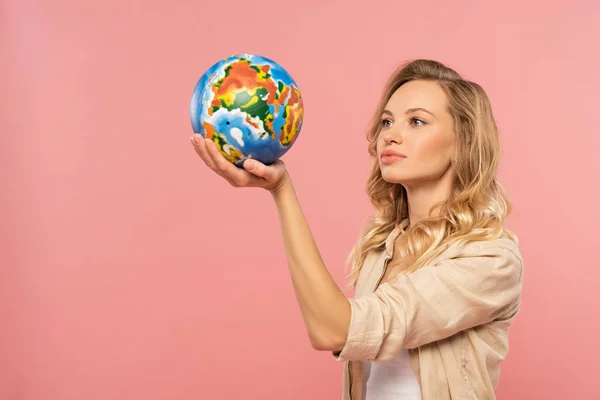 Blonde woman holding globe in hand isolated on pink — Stock Photo